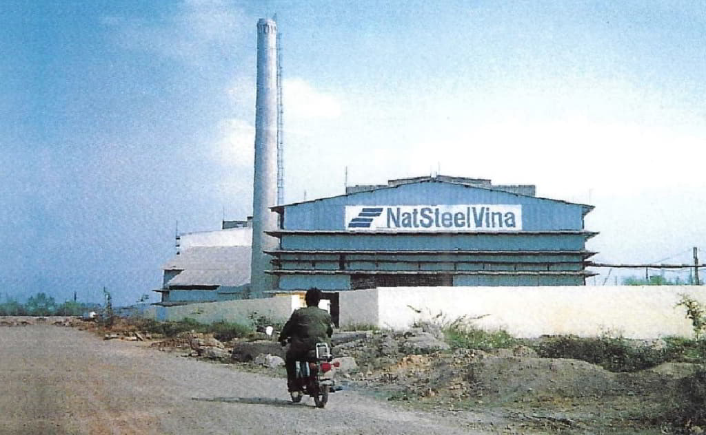 A person riding a motorcycle outside of a factoryDescription automatically generated with low confidence
